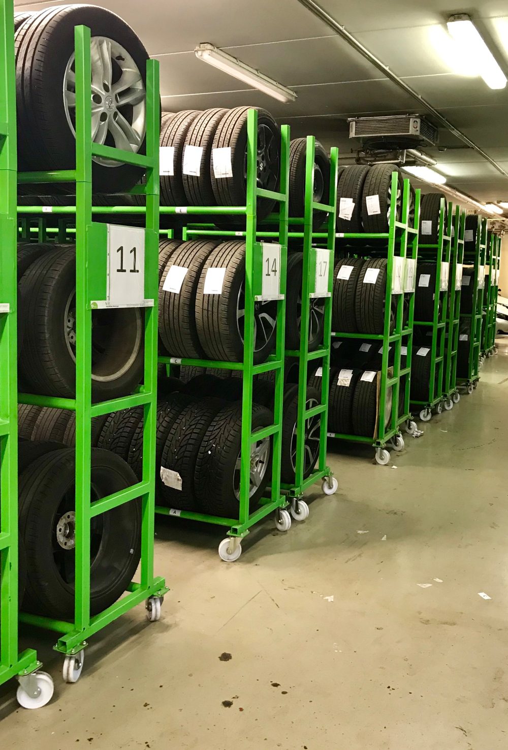 Mobiles Räderlager mit LoggyStore-Elementen: grüne, fahrbare Reifenregale in einem Lagerraum